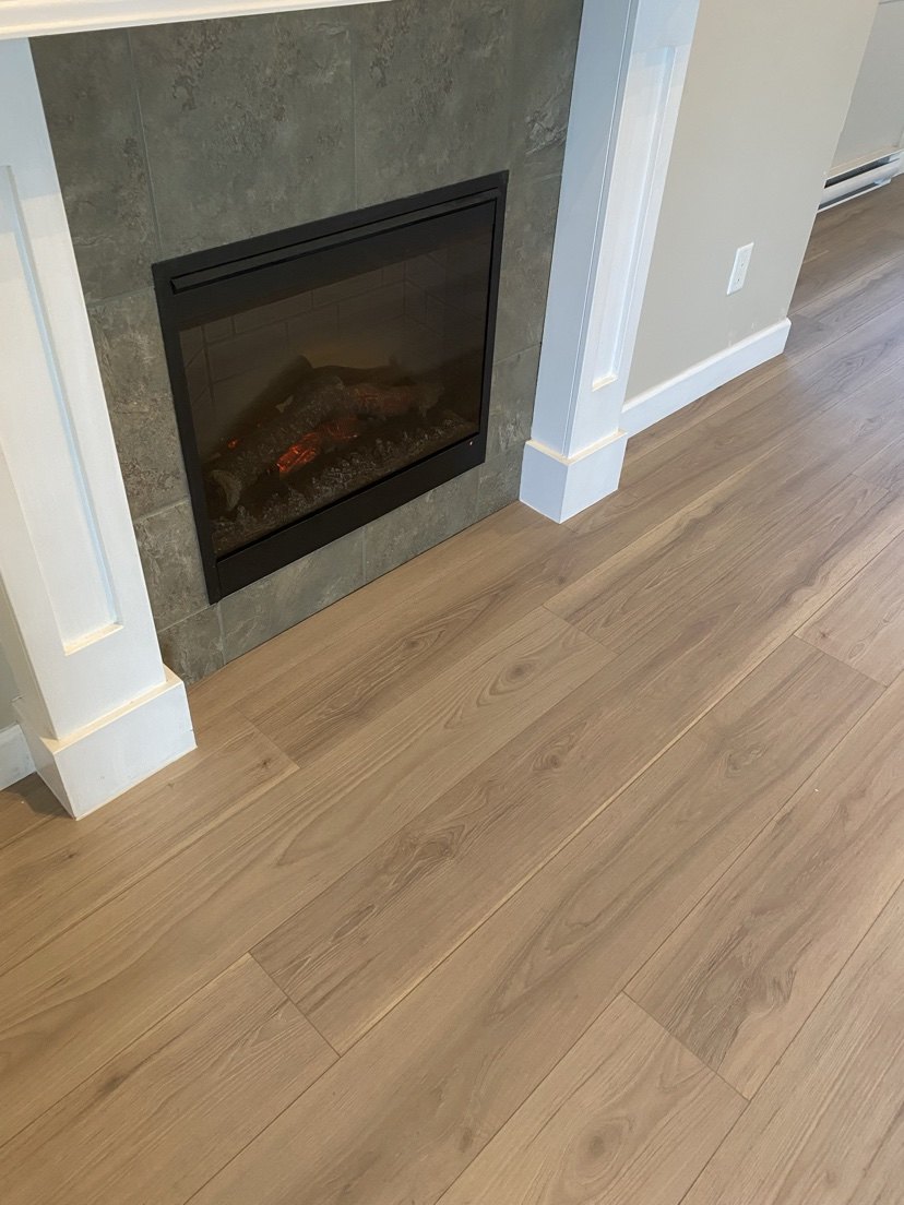Living room with light wood flooring around a tiled fireplace